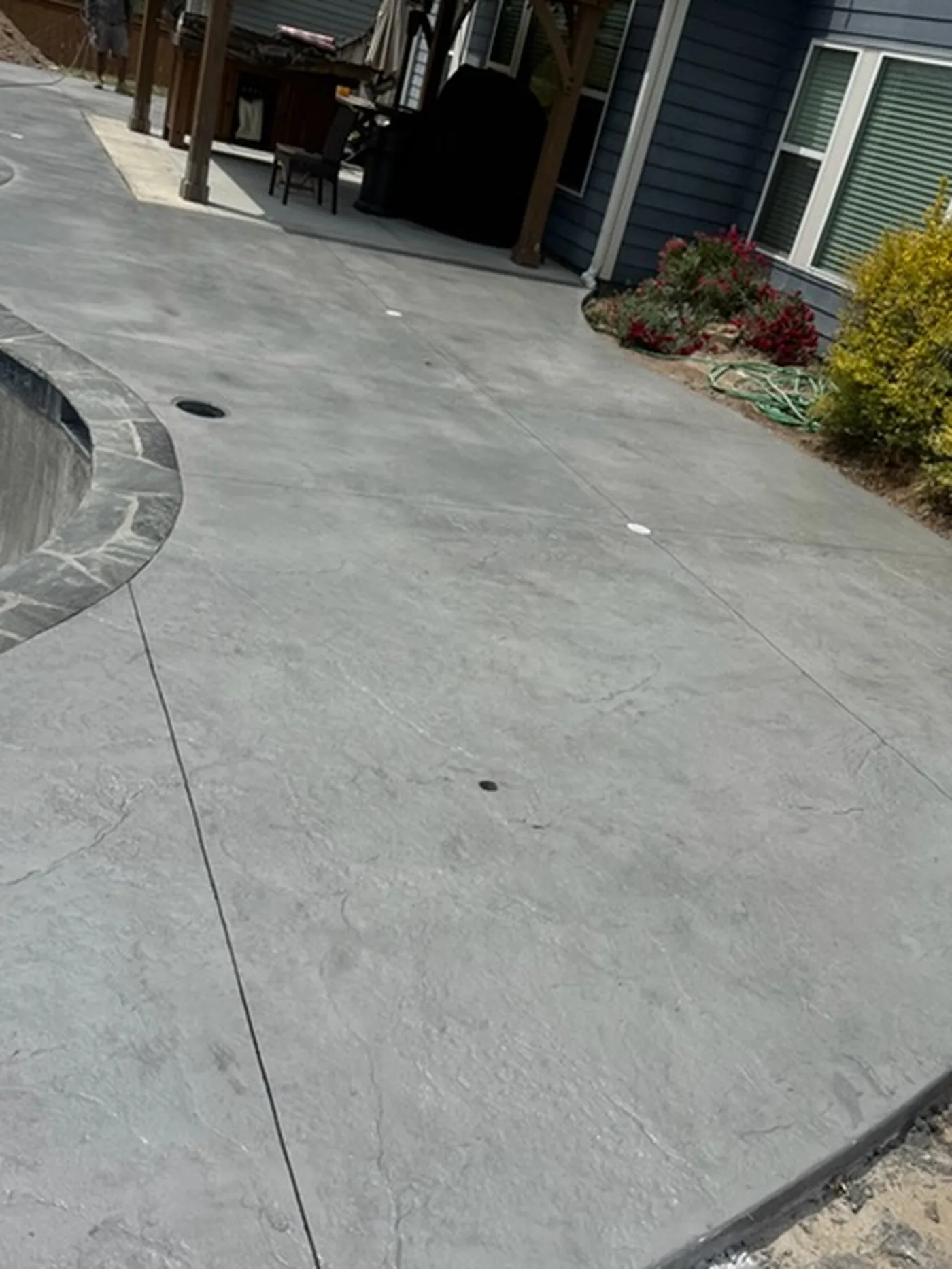 Stamped concrete patio curving along a pool deck beside a house