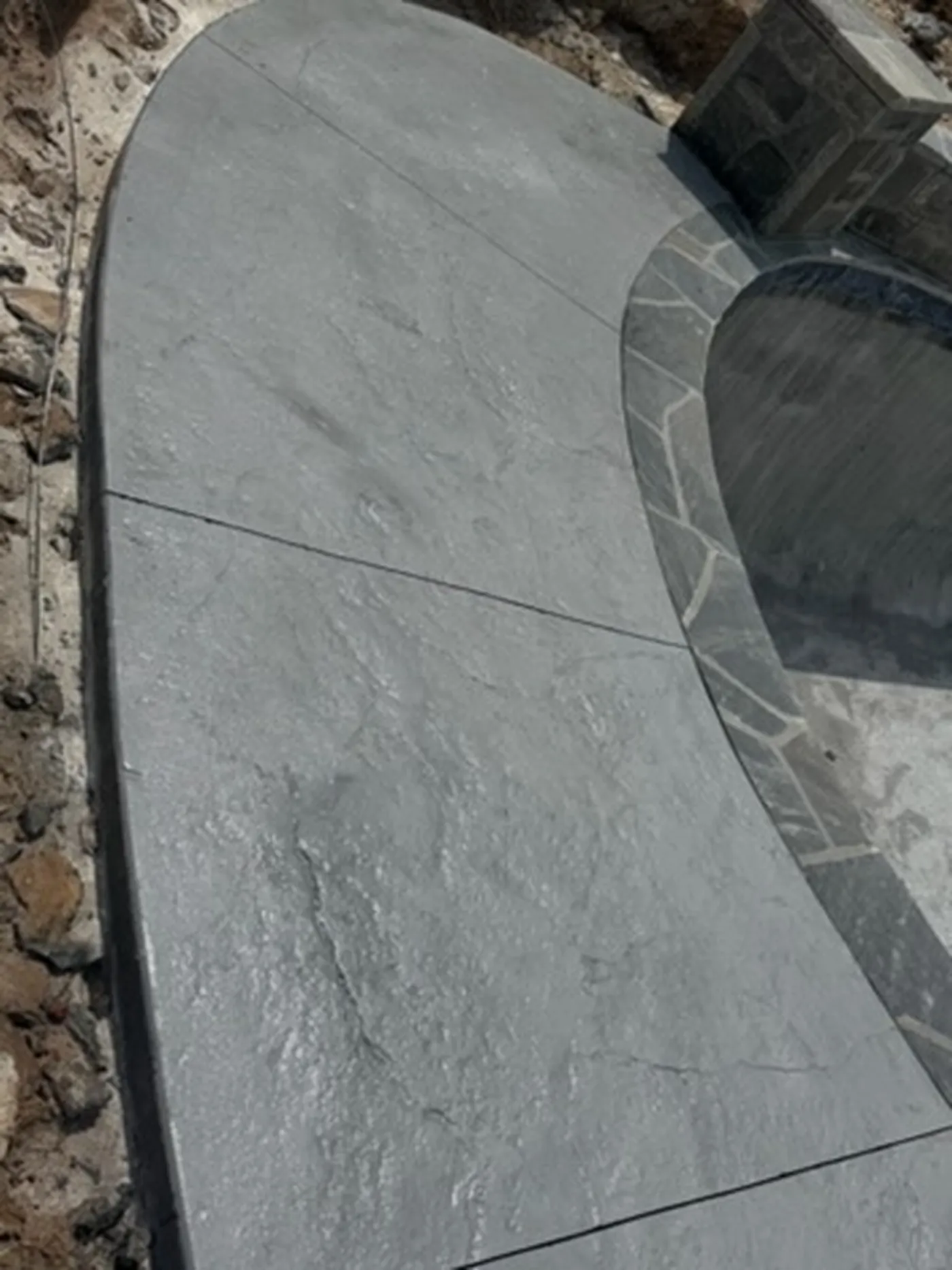 Curved stamped concrete walkway edged with natural stone