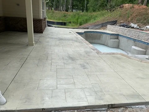 Stamped concrete patio under a covered porch beside a pool