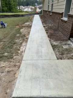 Long stamped concrete walkway running along the side of a house